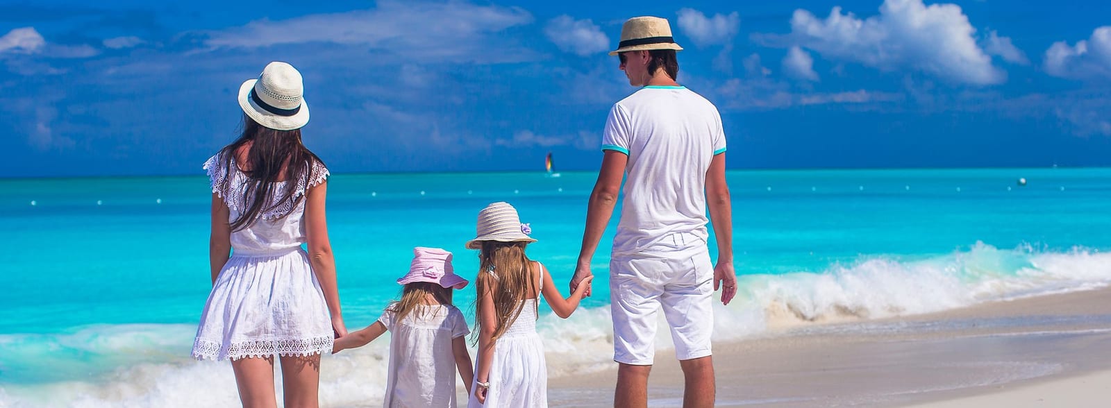 Family of four holding hands on a pristine tropical beach with turquoise water and white sand — book a fee-free vacation rental on Houfy. | Houfy — No Fees, Book Direct