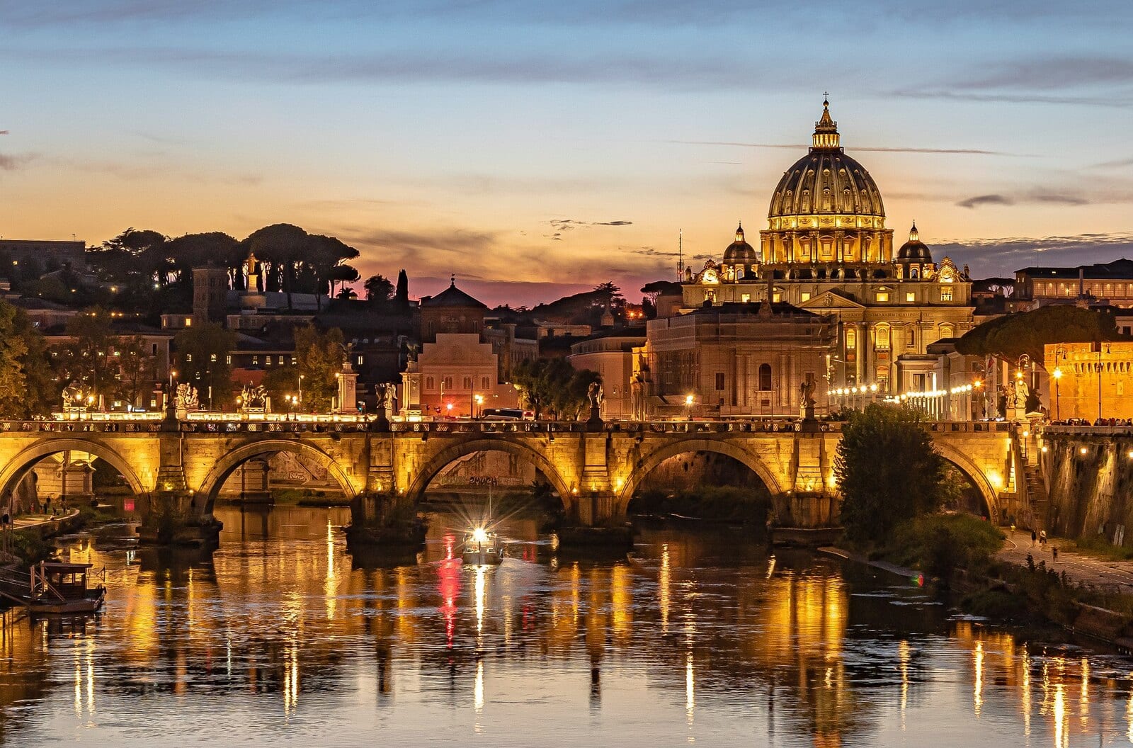 Sunset over Rome reveals the illuminated St. Peter's Basilica and a historic bridge reflecting on the Tiber River, capturing the city's blend of ancient architecture and vibrant evening ambiance. | Houfy — No Fees, Book Direct