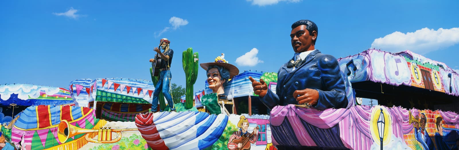 Colorful amusement park scene in Düsseldorf featuring large cowboy-themed sculptures on a carousel against a clear blue sky, attracting visitors with its vibrant, whimsical decor. | Houfy — No Fees, Book Direct