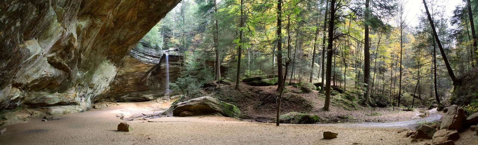 Ash Cave in Hocking Hills, Ohio, features a striking rock overhang with a cascading waterfall set against a lush forest backdrop, presenting a serene natural escape for visitors. | Houfy — No Fees, Book Direct
