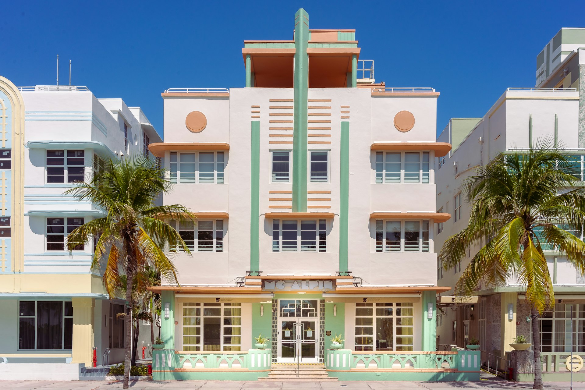 Pastel Art Deco facade on South Beach under a clear blue sky with palm trees