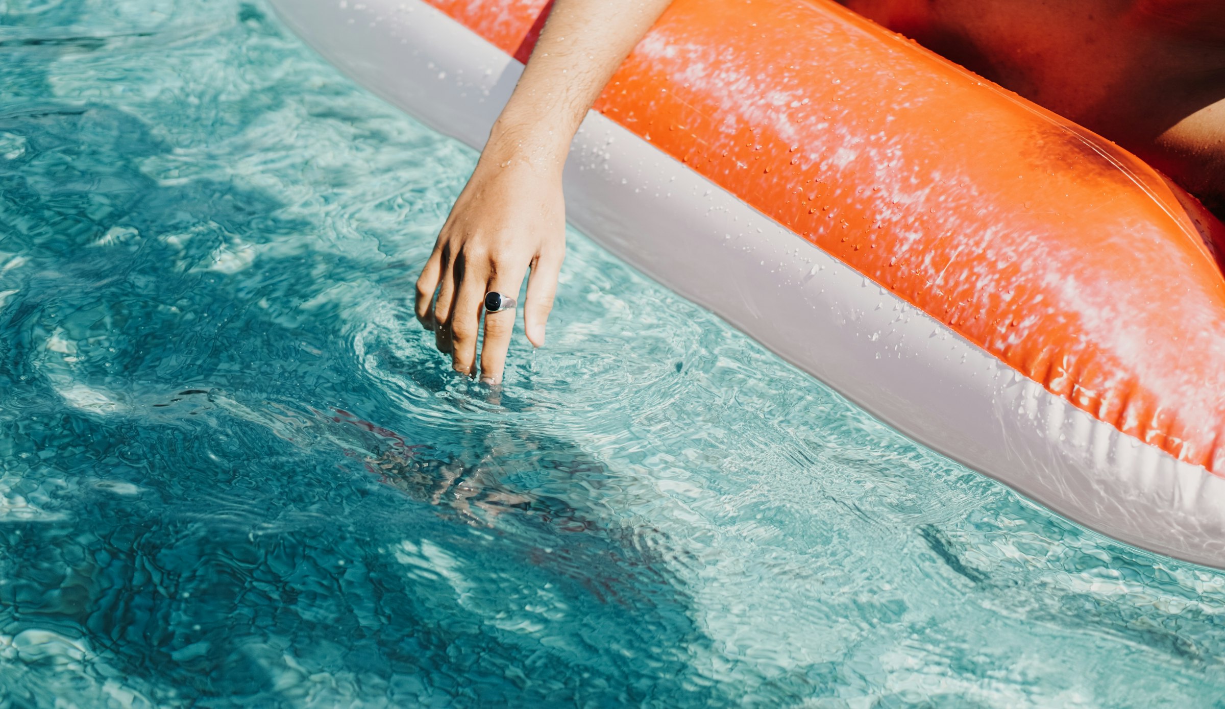 Hands breaking the surface of clear blue pool water