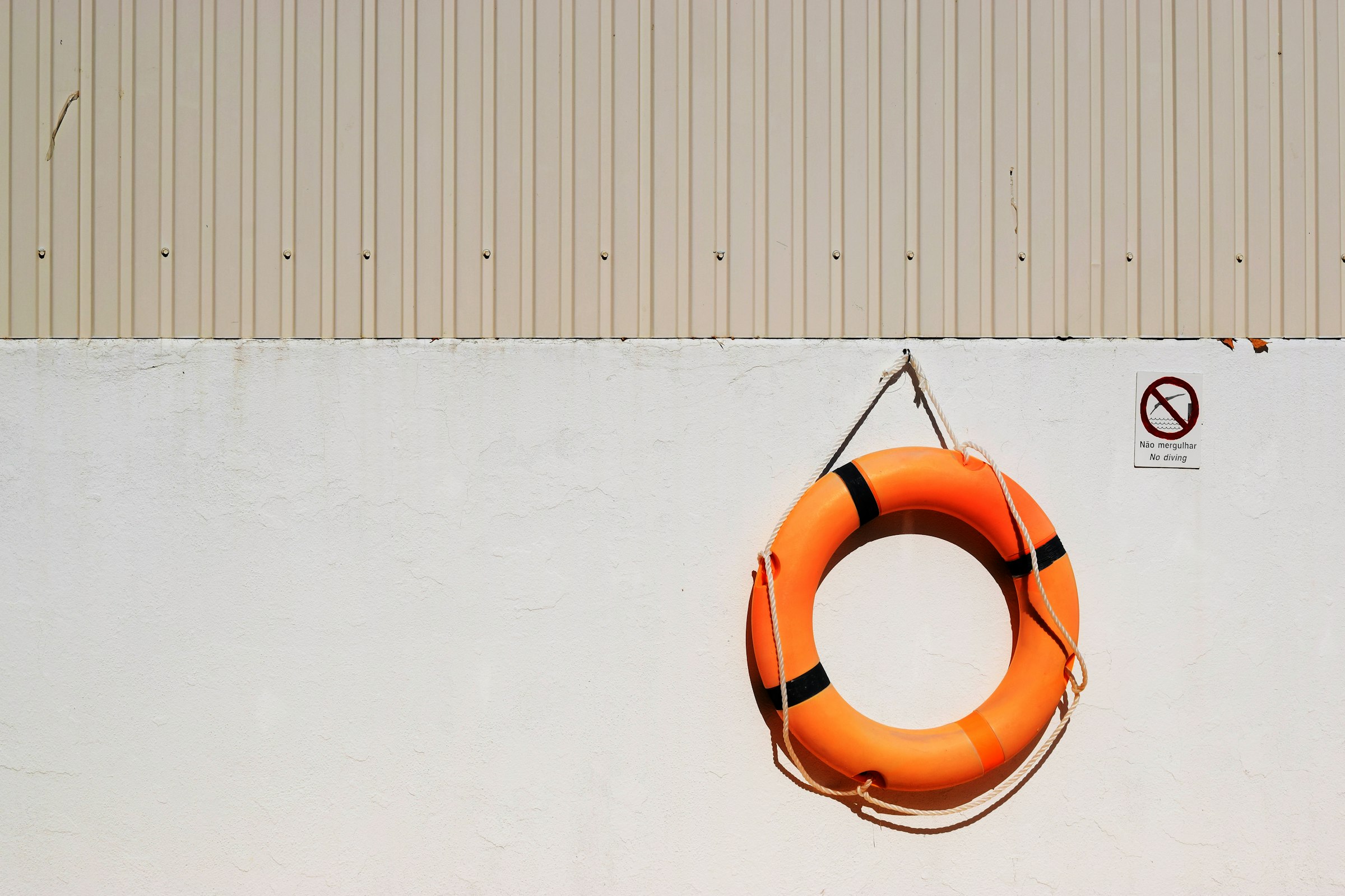 A round white and red life buoy mounted beside a pool