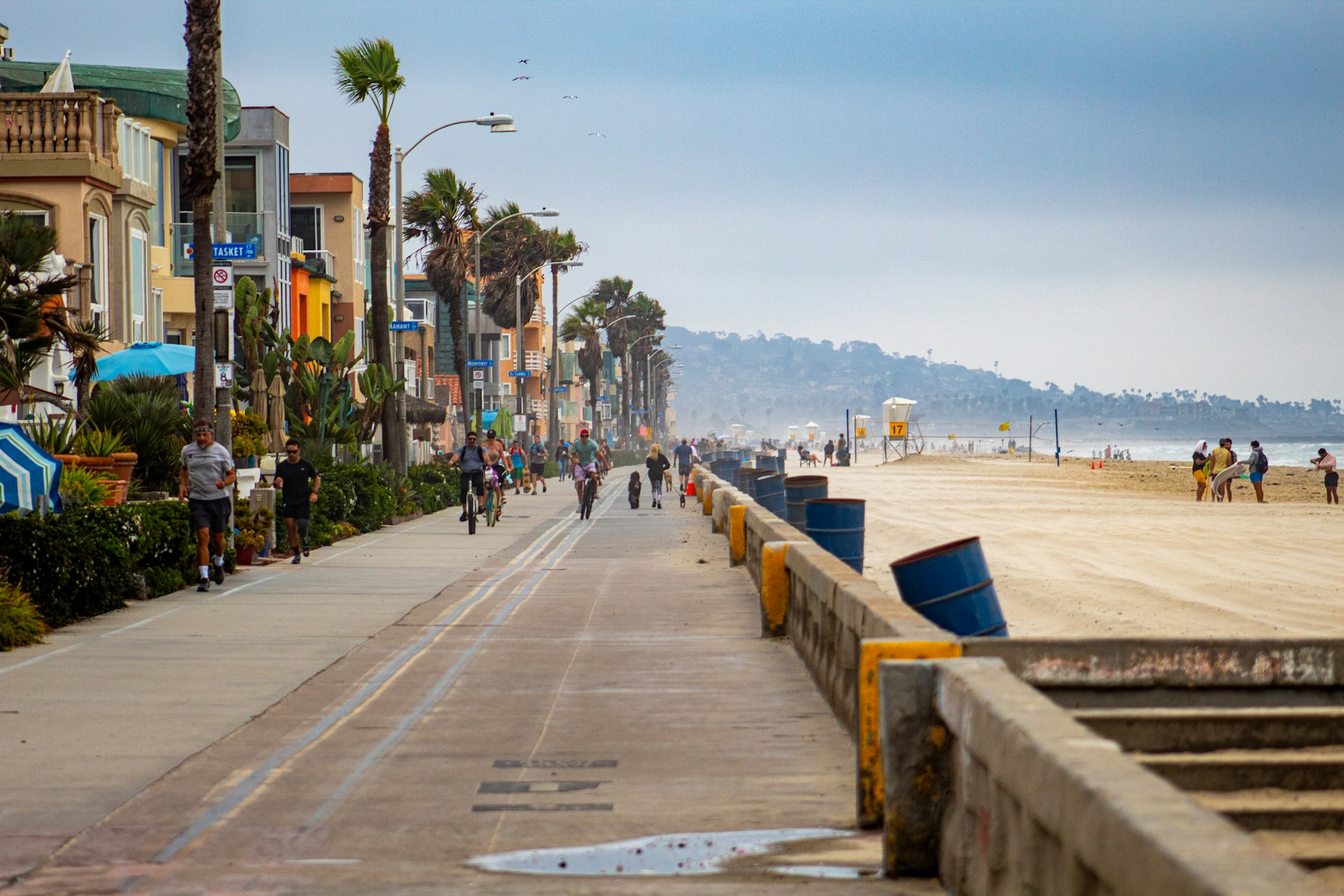 People walking the Mission Beach boardwalk beside the Pacific on a clear day