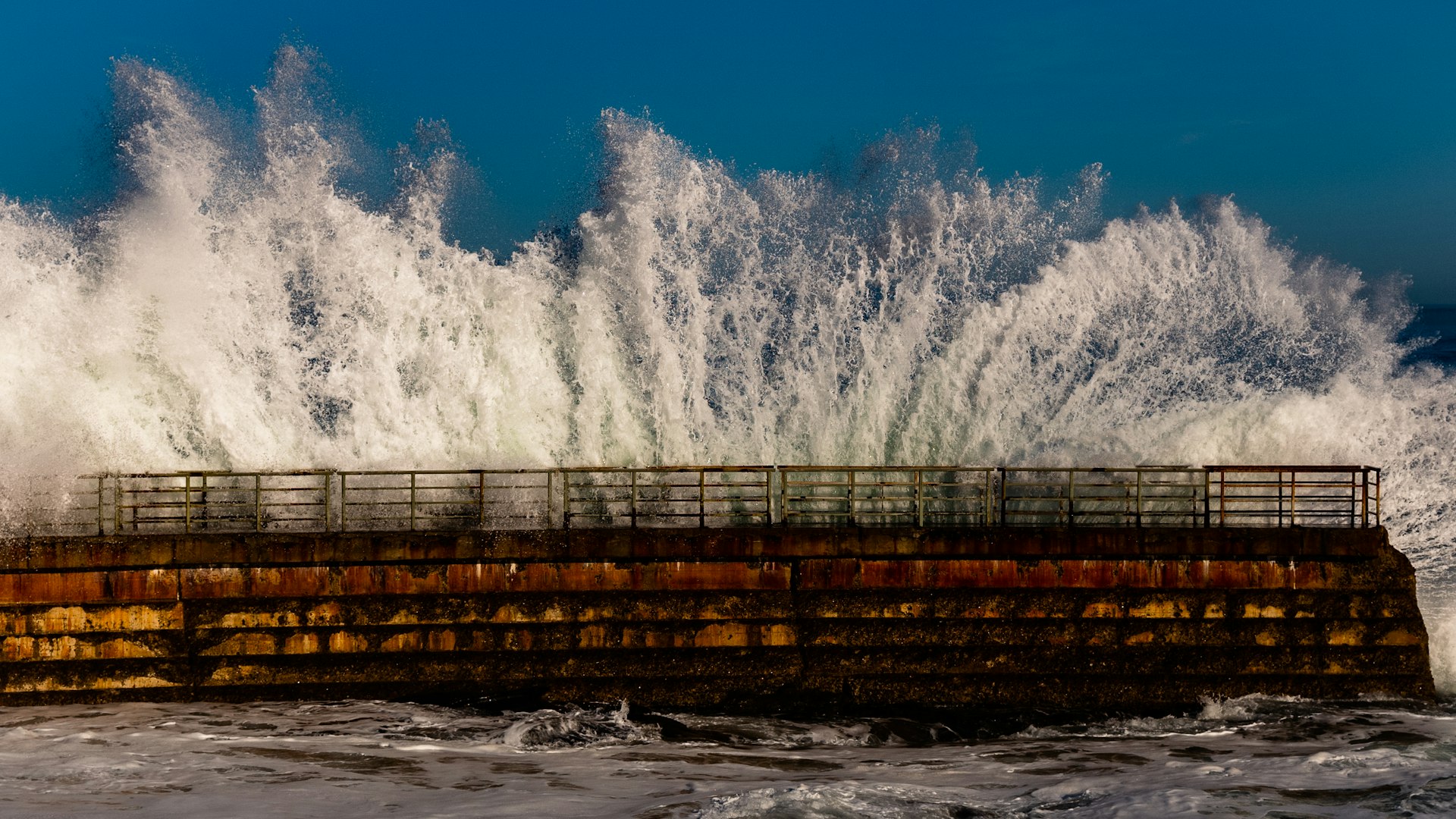 Large wave crashing over a coastal pier structure at La Jolla