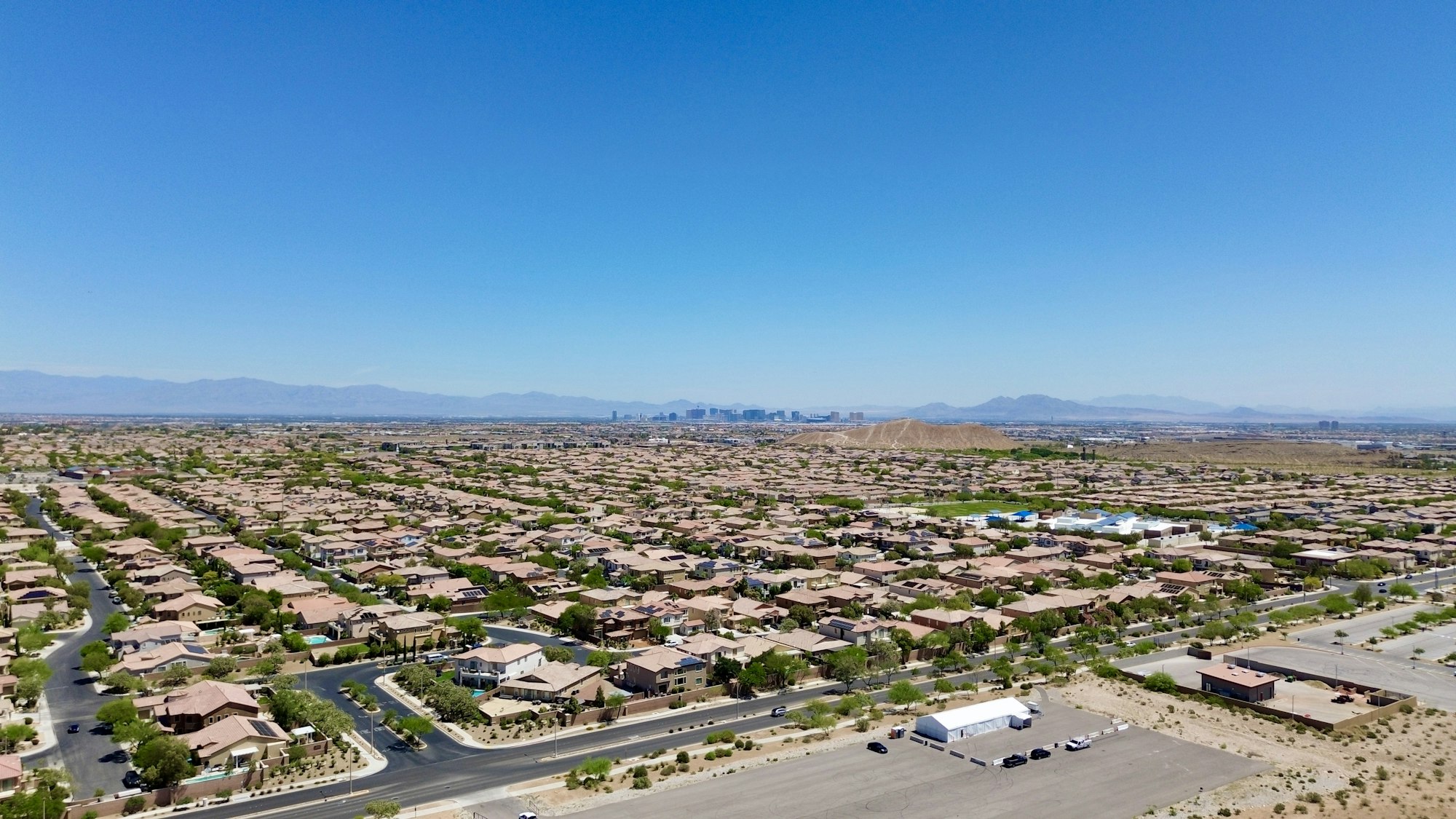 Aerial view of a Las Vegas desert neighborhood with suburban streets and the city skyline on the horizon