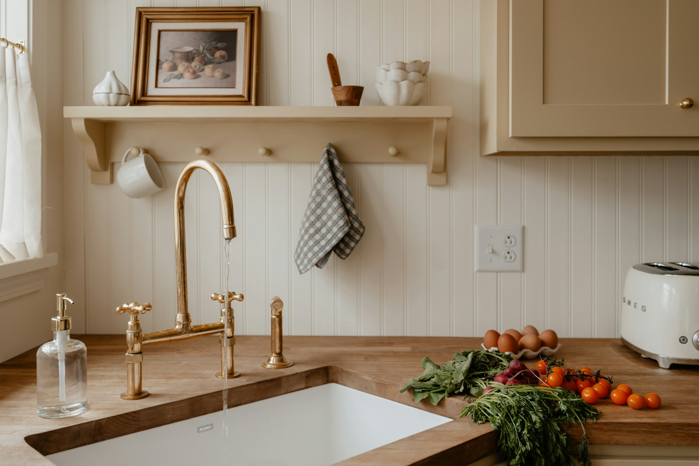 A kitchen sink and open shelf with groceries and everyday supplies