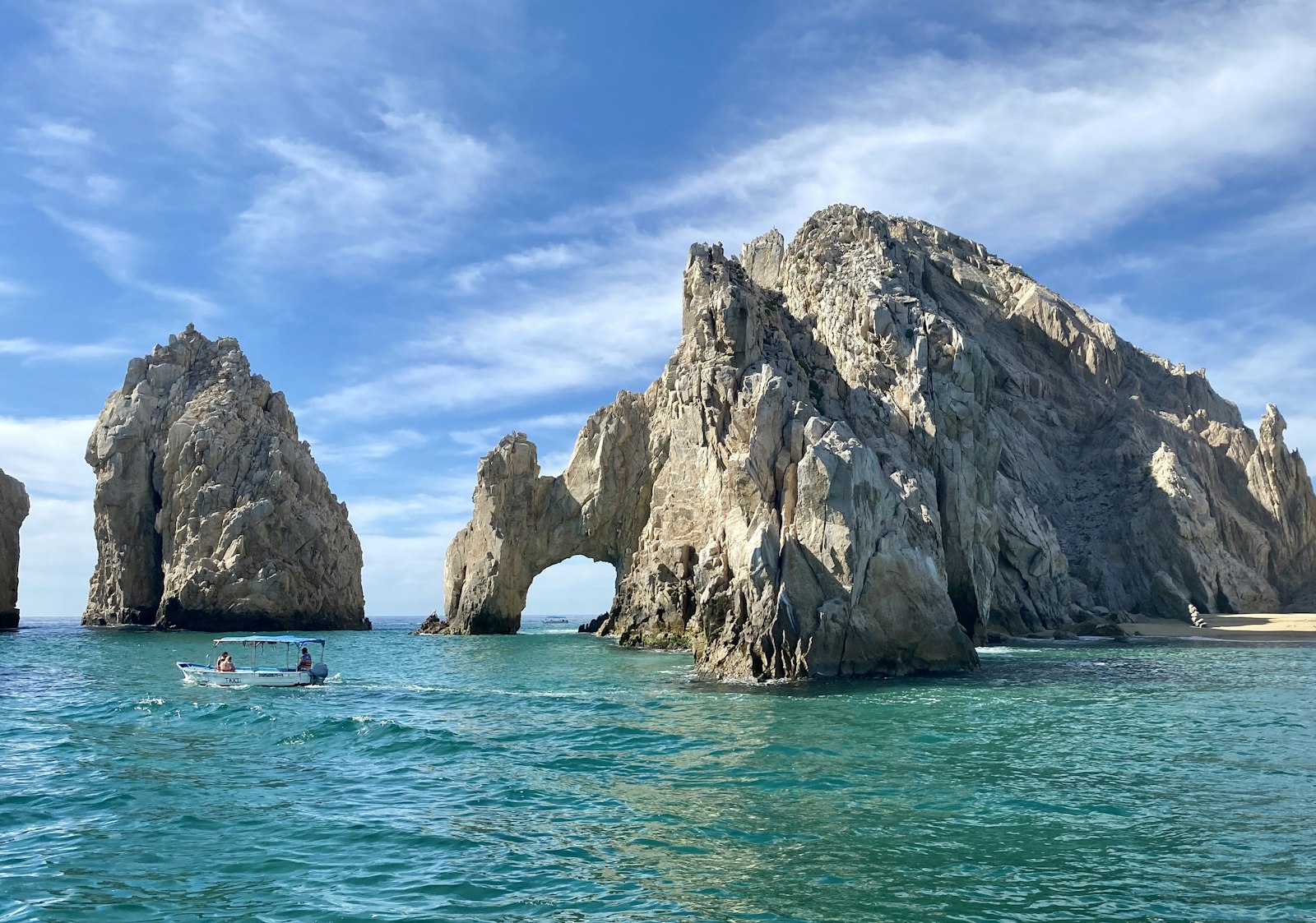 El Arco rock arch at Land's End with turquoise water and a small sandy cove