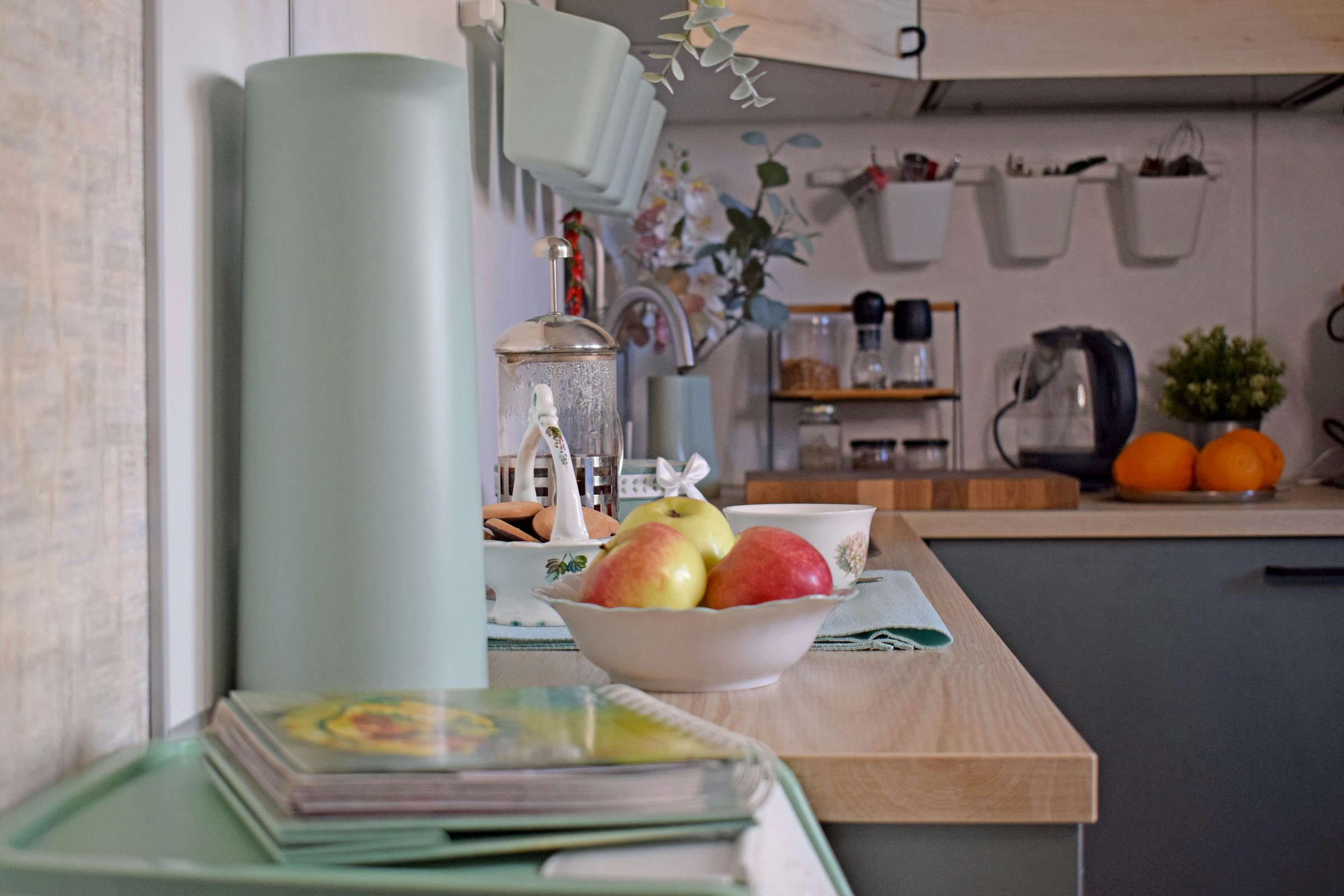 A kitchen counter with fruit, jars and everyday items laid out along a light worktop