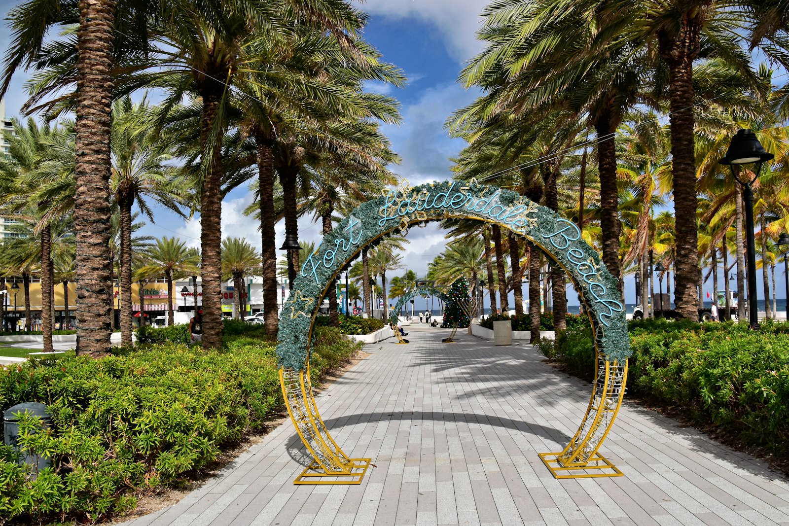 Archway sculpture on a palm-lined promenade leading toward Fort Lauderdale Beach