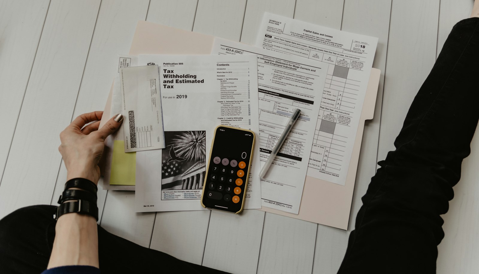 Calculator, pen, and paper worksheets used for tax and budget calculations