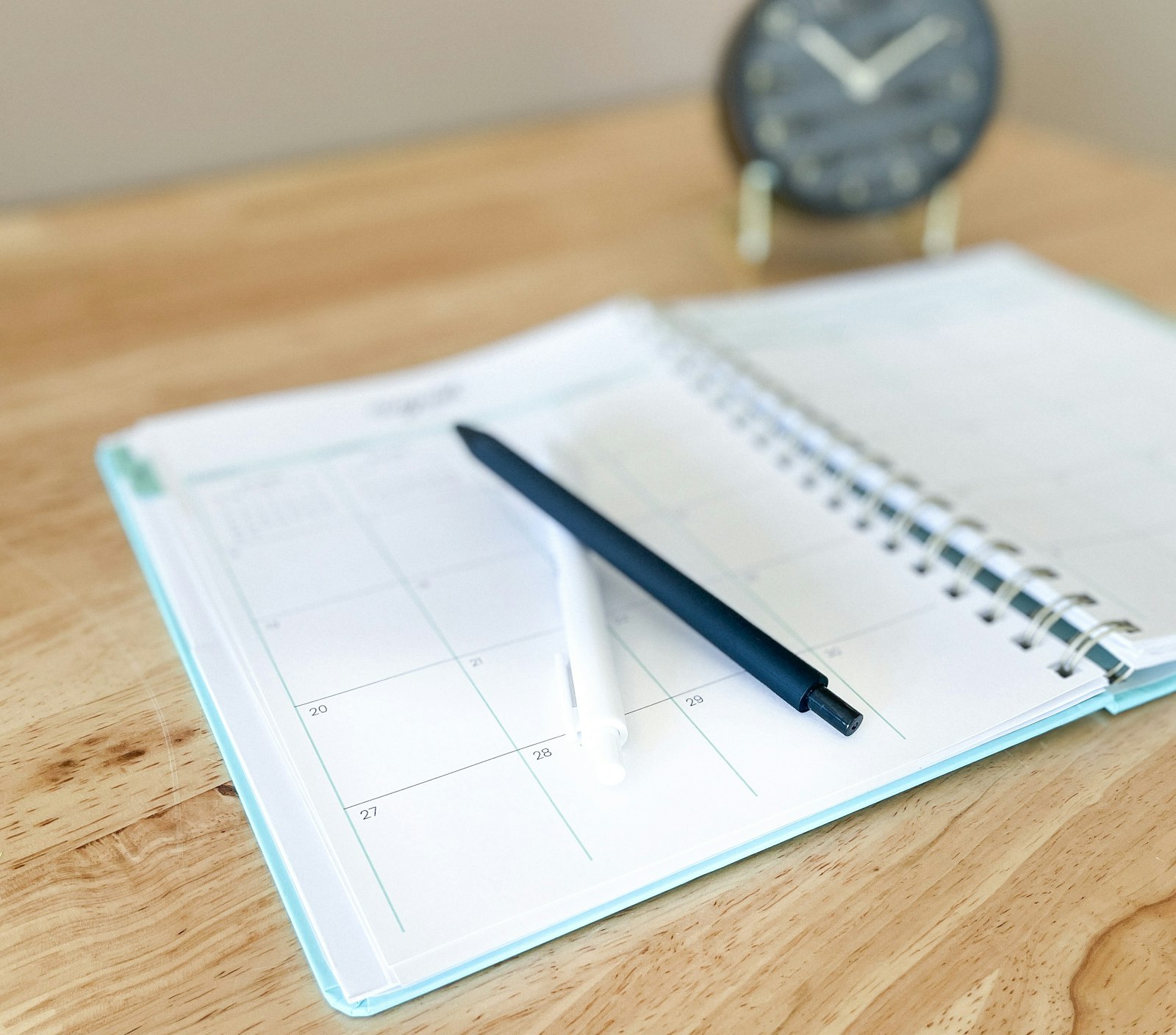 Open paper planner with a pen on a wooden desk