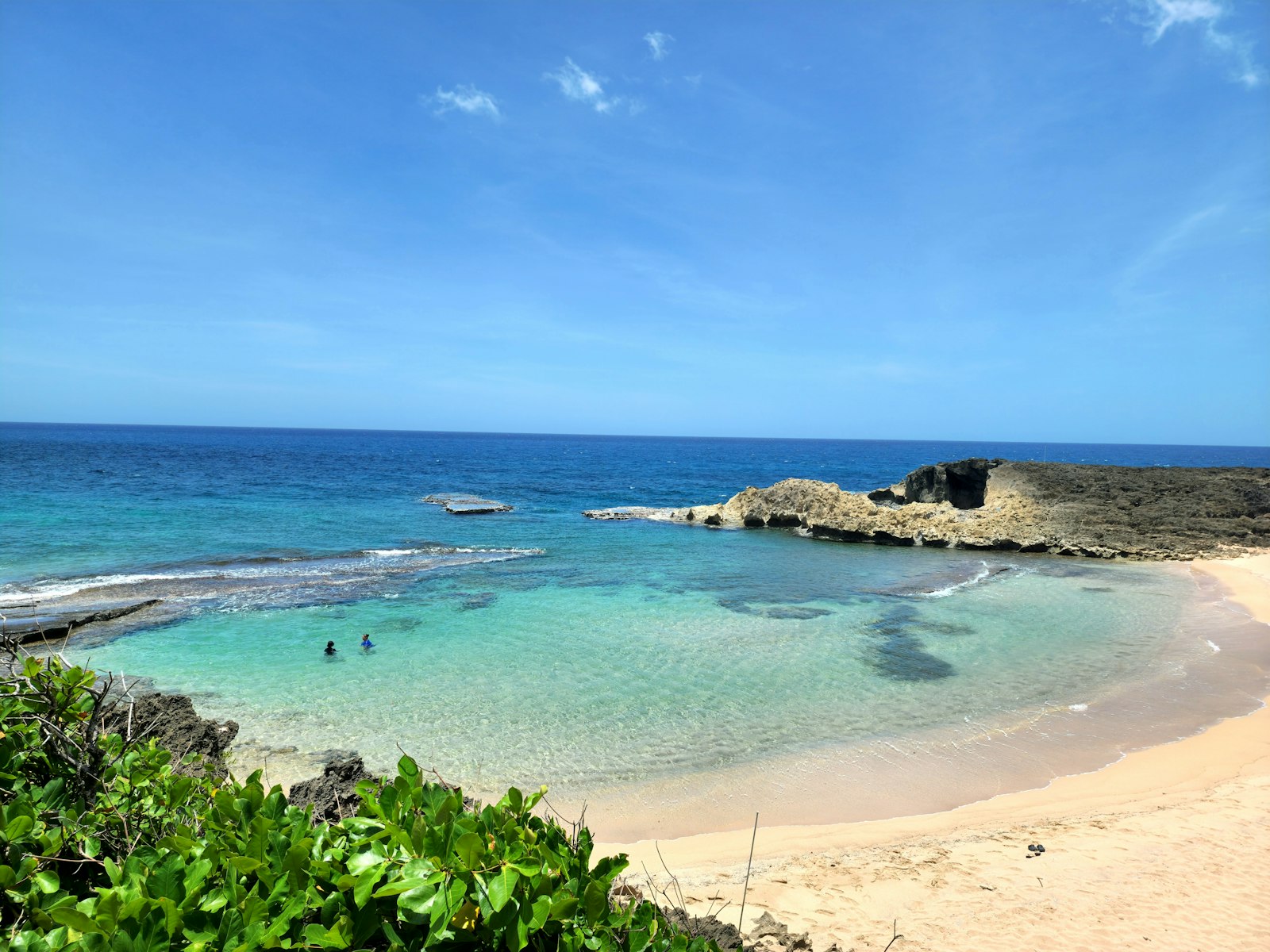 Turquoise cove with clear shallow water, a sandy beach, and a rocky headland in Puerto Rico