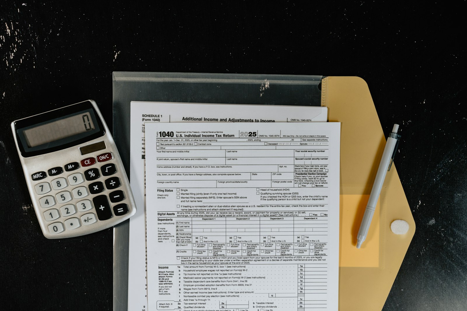 Calculator and tax forms on a dark desk