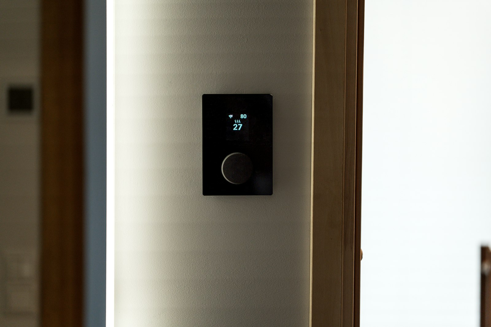 Modern black smart thermostat mounted on a wall