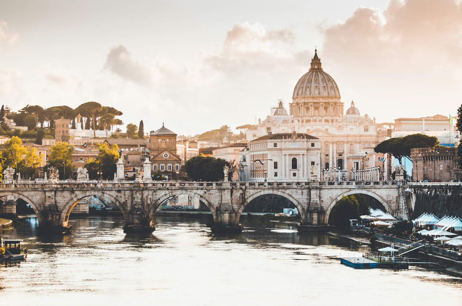 Saint Peter's Basilica and a stone bridge over the Tiber in warm light