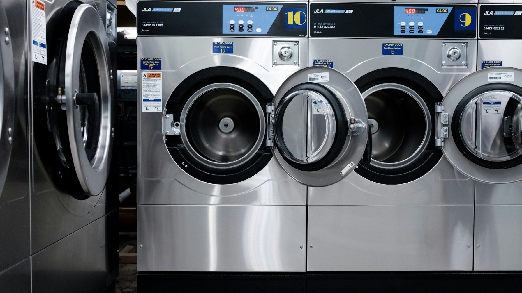 A row of front-loading washing machines in an empty launderette at night