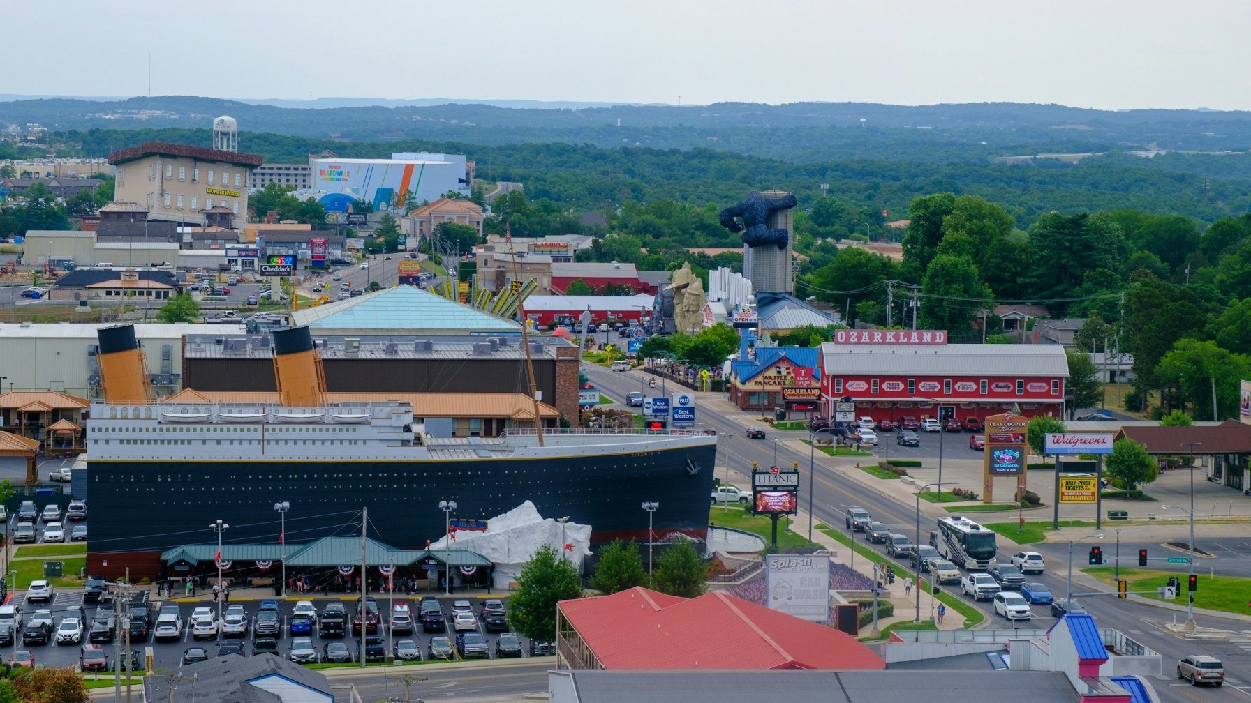A busy road lined with attractions in Branson, Missouri, including a large ship-shaped building, seen from above on an overcast day