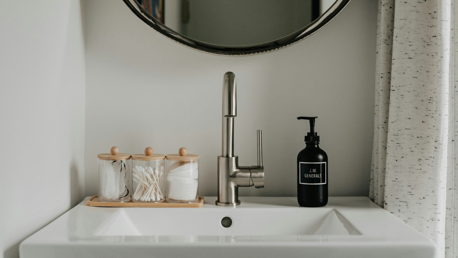 A clean white bathroom basin with a soap dispenser beside it and a mirror above