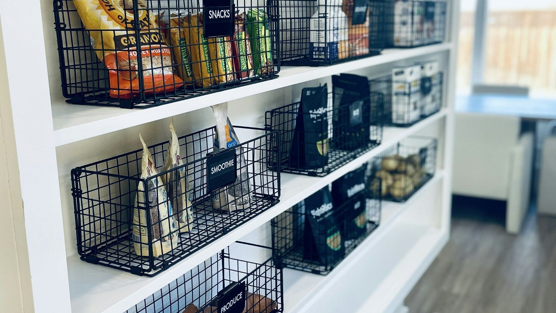 Wire baskets on white open shelving, each holding a different category of supplies