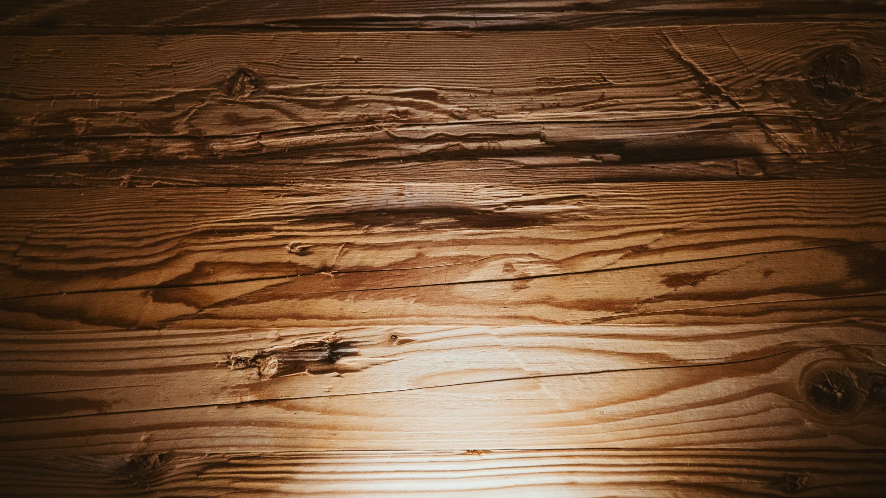 Close detail of a worn wooden floor with daylight falling across the grain