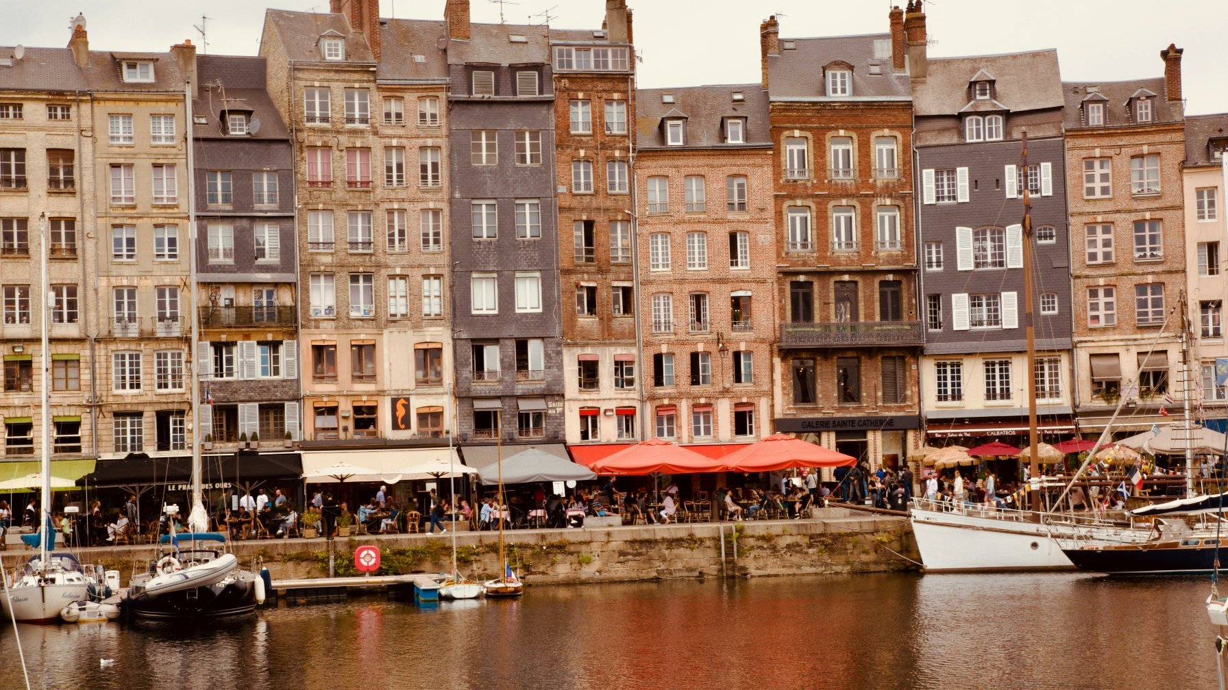 The tall narrow houses of Honfleur reflected in the water of the Vieux Bassin