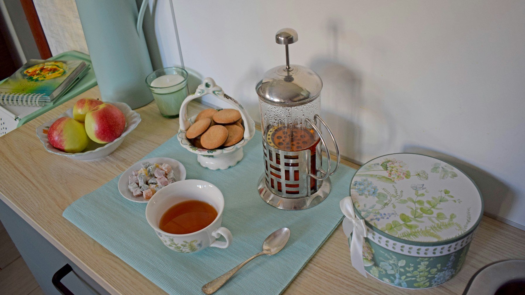 A welcome tray with fruit, biscuits, cups and a cafetiere on a kitchen table