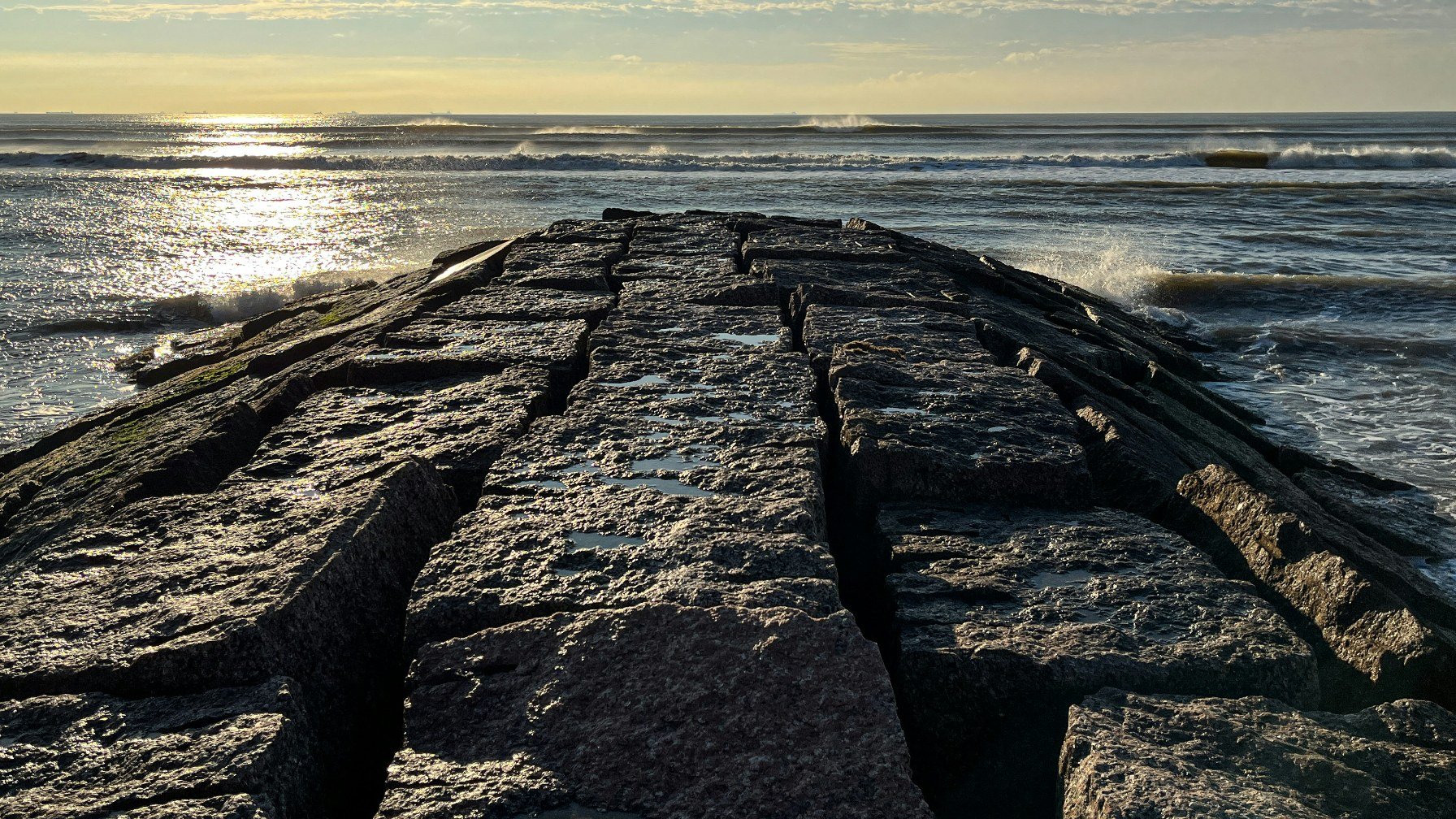 Sunrise over the Gulf seen across the rocks of a Galveston jetty