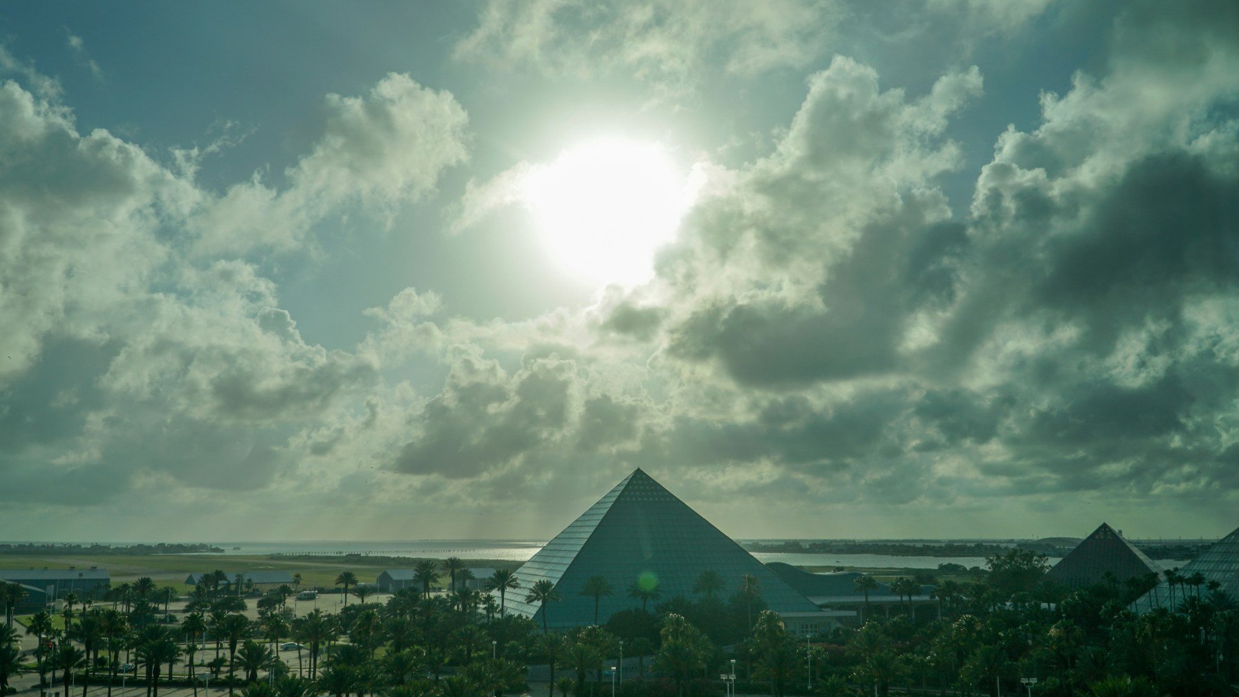 The glass pyramids of Moody Gardens in Galveston under a bright, cloud-filled sky