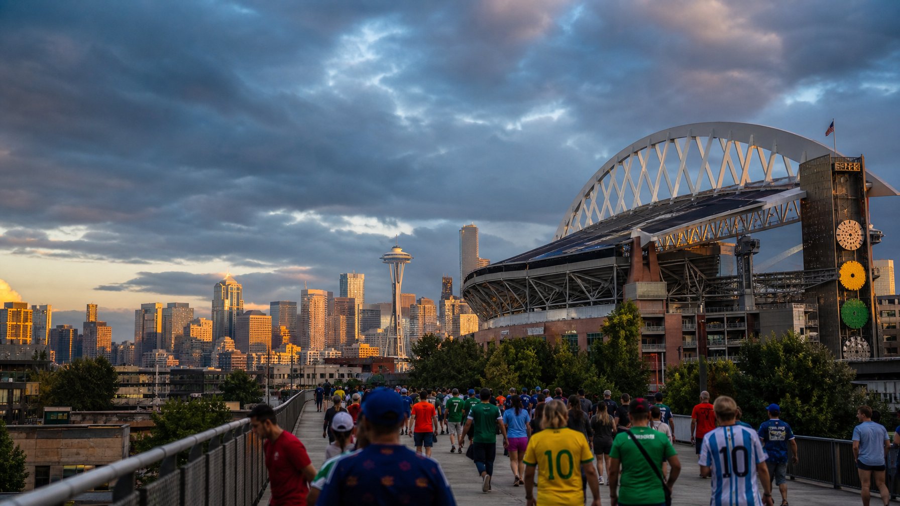 World Cup fans in international jerseys crossing a pedestrian bridge toward Lumen Field with the Seattle Space Needle and city skyline glowing at golden sunset