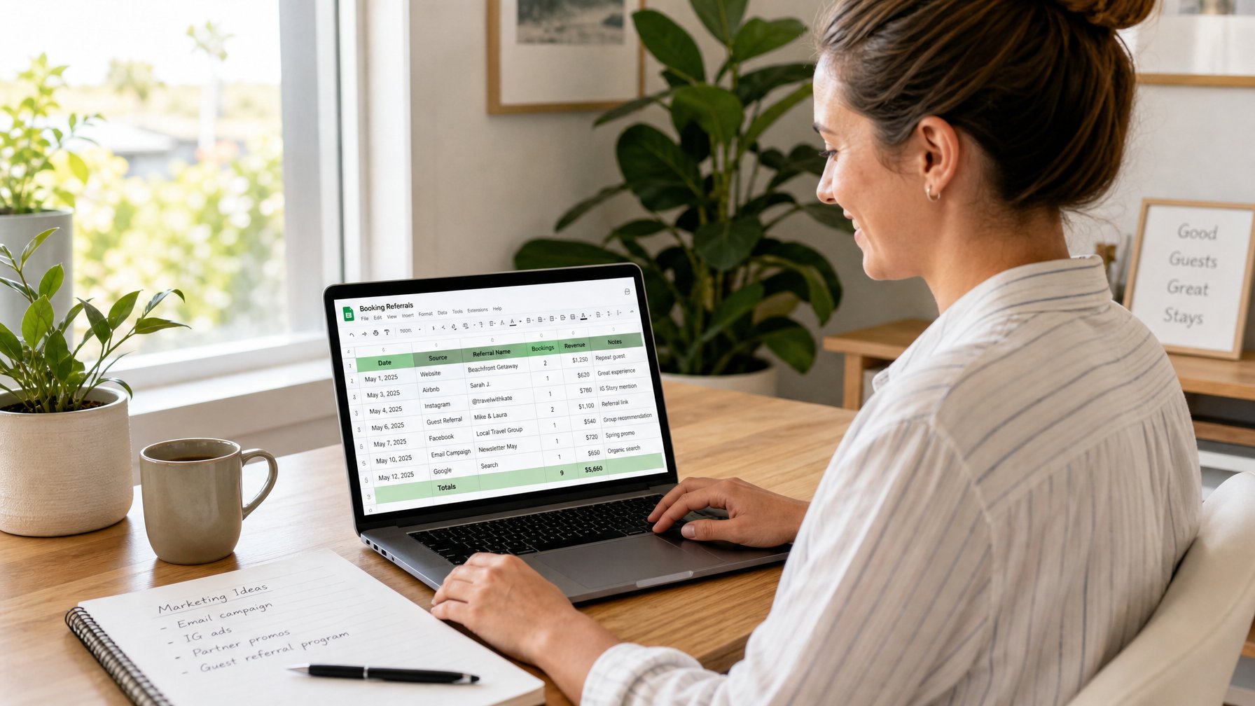 A vacation rental host smiling at a laptop in a bright home office, reviewing a referral tracking spreadsheet with plants and natural light in the background