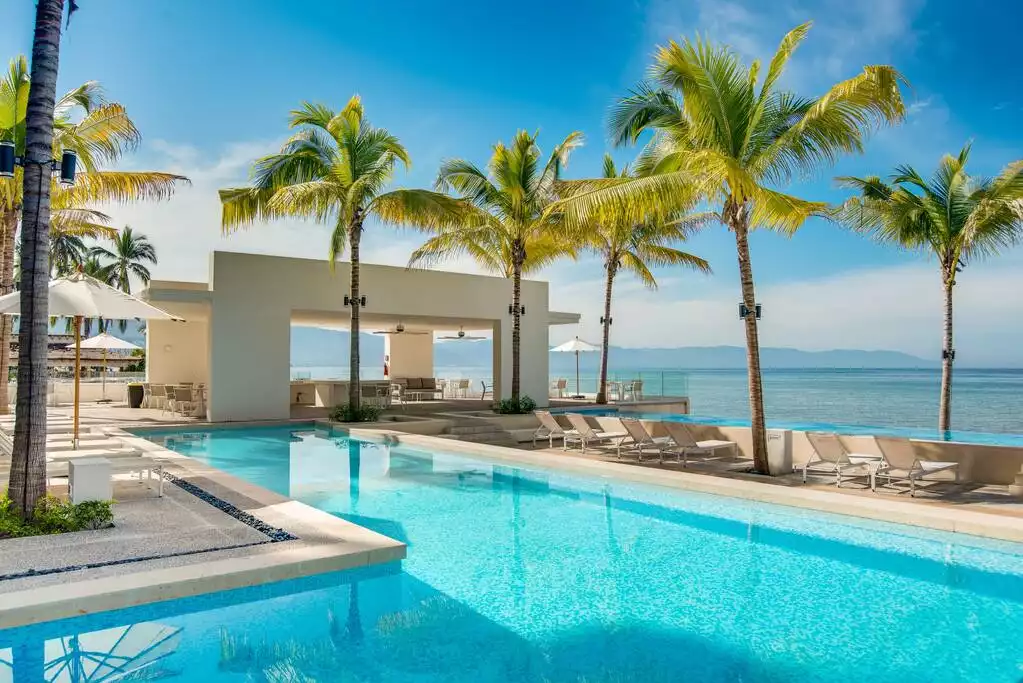 The resort like pool area has ample chairs, tables and umbrellas.
