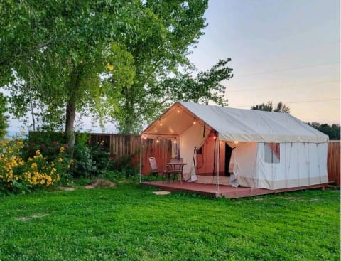 The two glamping tents are located in a beautiful flower garden and clover lawn, each with fairy lights and a porch to sit on.