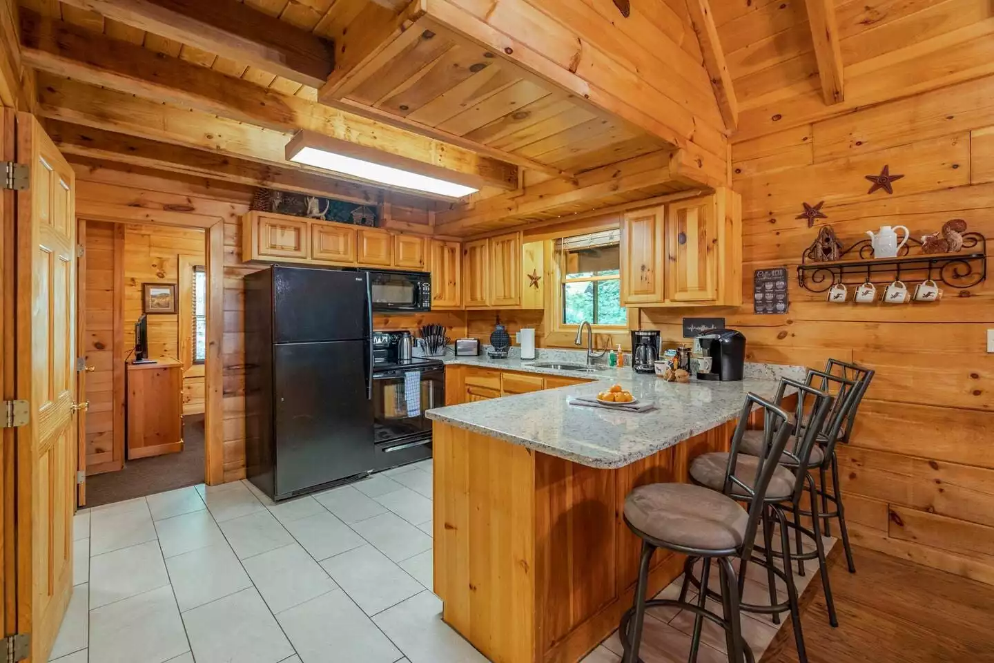 Enjoy the convenience of granite countertops, a breakfast bar with comfy high chairs, and a fully equipped kitchen to make yourself feel right at home here. - Creekside Serenity Cabin - Pigeon Forge