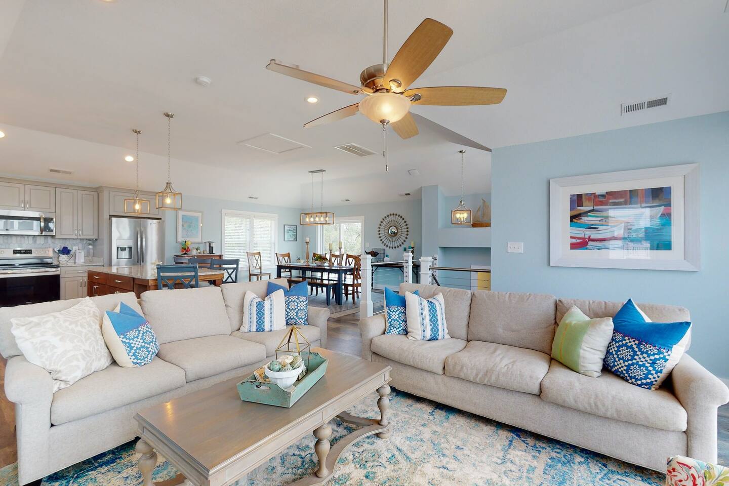 The airy living room features beautiful flooring, providing a warm and inviting ambiance with the option of heat if needed. With an open design and ceiling fan.