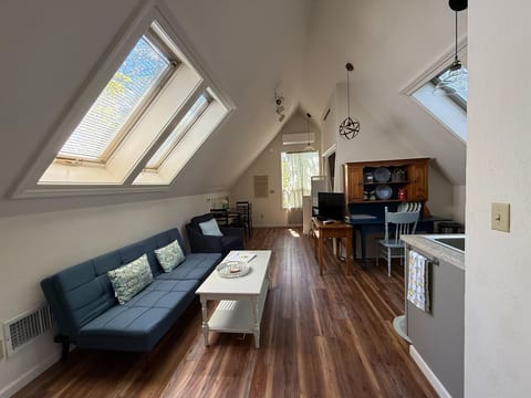 View of studio living space from bed (open to sitting/TV viewing area), hutch and kitchenette, dining area.