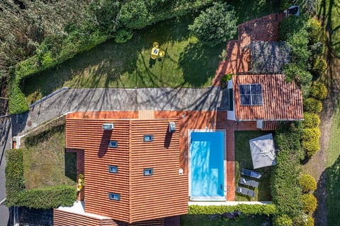 A striking aerial view of the home with its glistening blue pool and charming rooftop windows.