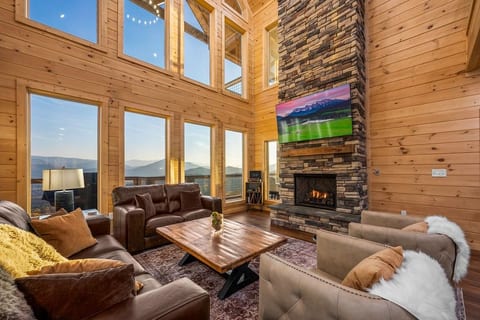 Living room with Floor to Ceiling Stone Gas Fireplace with 70" 4K Smart TV including YouTube TV and Netflix, and Large Picture Windows