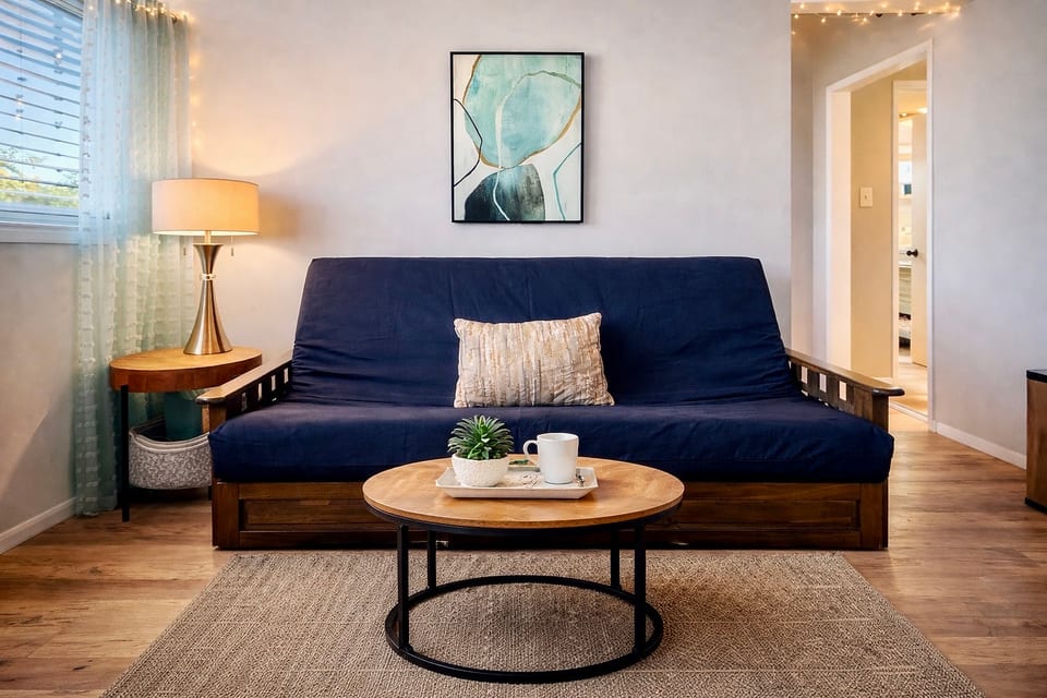 Cozy living room with futon (linens in the bin) smart TV and vaulted ceiling.