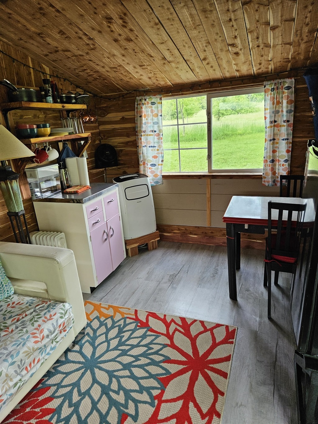 Indoor kitchenette area provides plates, mugs, silverware, coffee and coffee making supplies, AC unit in corner, small table for two for games, eating, reading, etc... - Cedar Bungalow - Peaceful & Relaxing Farm Getaway - Hartsburg