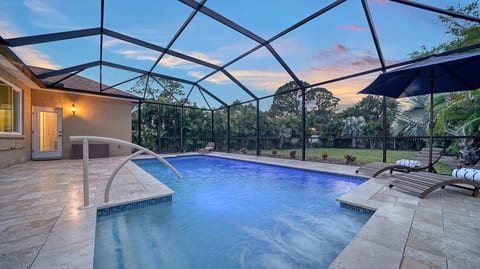 Screened pool oasis with loungers, travertine deck & sunset views