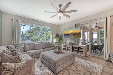 The sunlit Family Room with sparkling swimming pool views, an expansive L-shaped couch, oversized ottoman, children's books, games, and Smart TV for endless entertainment options, make it the perfect hub for relaxation and family fun!