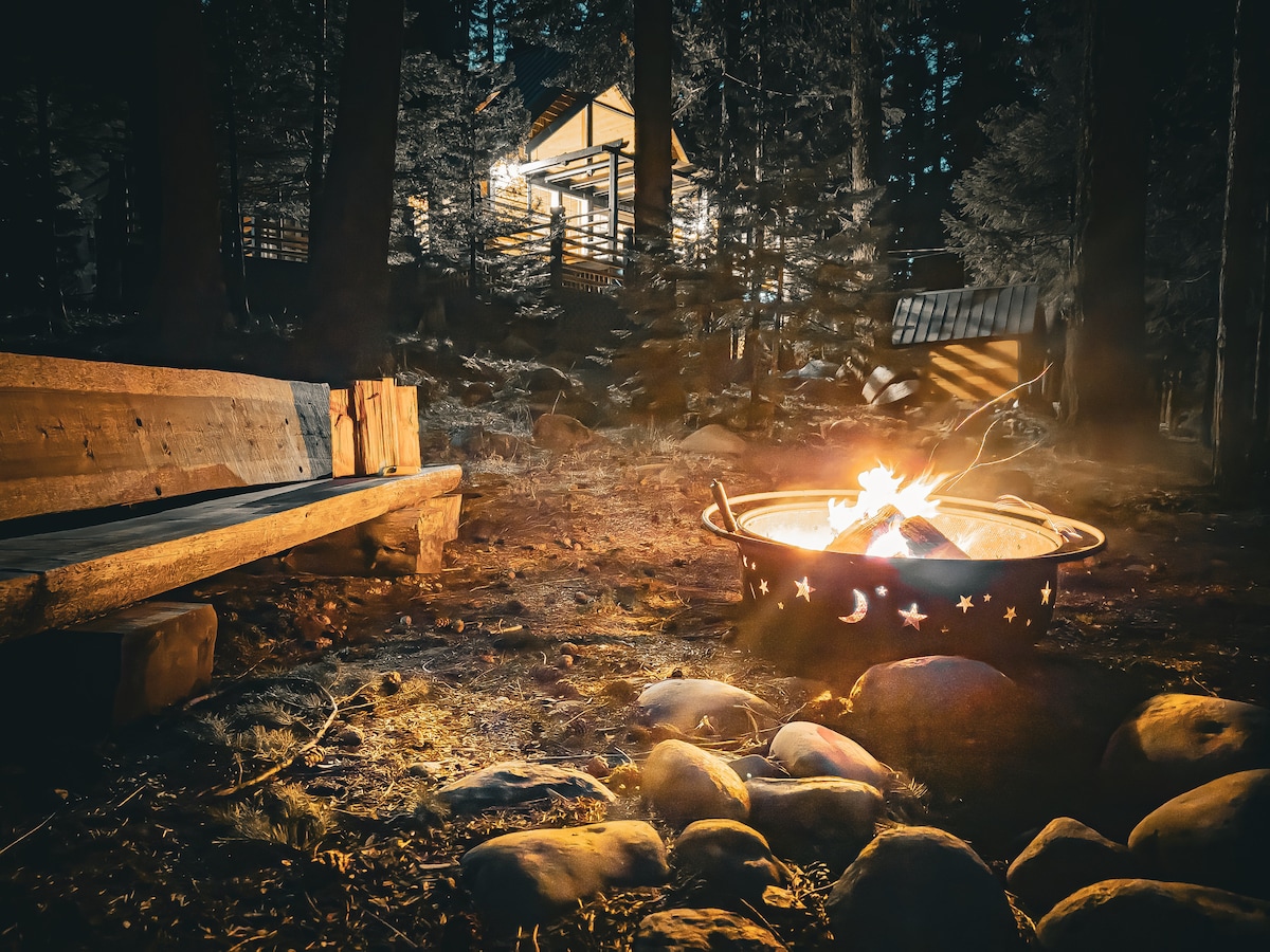 Fire pit and bench along the creek at night under starry skies and whispering pines Lassen creekside cabin