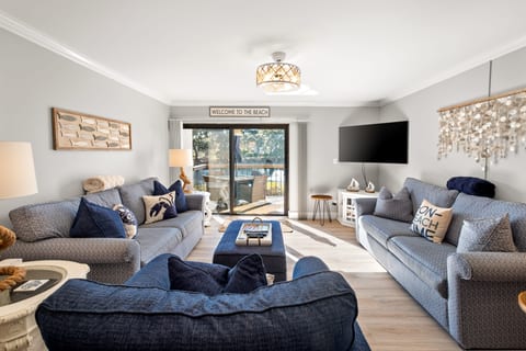 Living room with 2 full size couches (one is a queen sleeper) and oversized plush chair leading to private deck overlooking serene lagoon