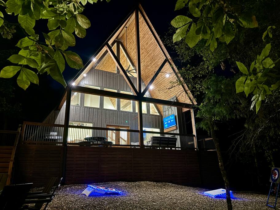 YAY frame cabin glowing at night with scenic forest surroundings in Hochatown, OK.