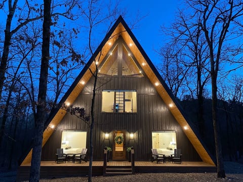 Warmly lit Yay frame cabin surrounded by tranquil forest at dusk in Broken Bow / Hochatown, OK.