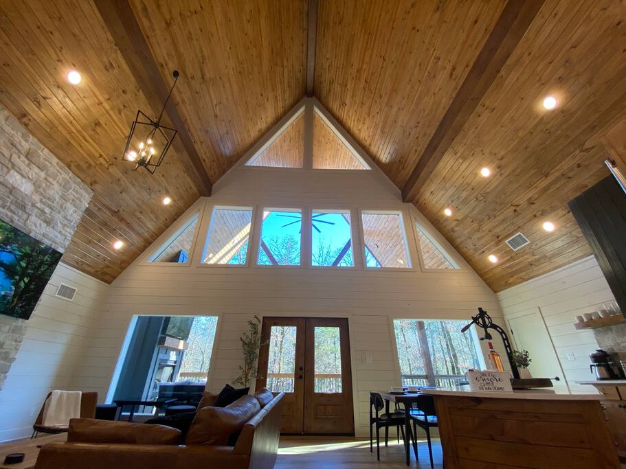 Rustic cabin living room with vaulted ceiling and large windows.