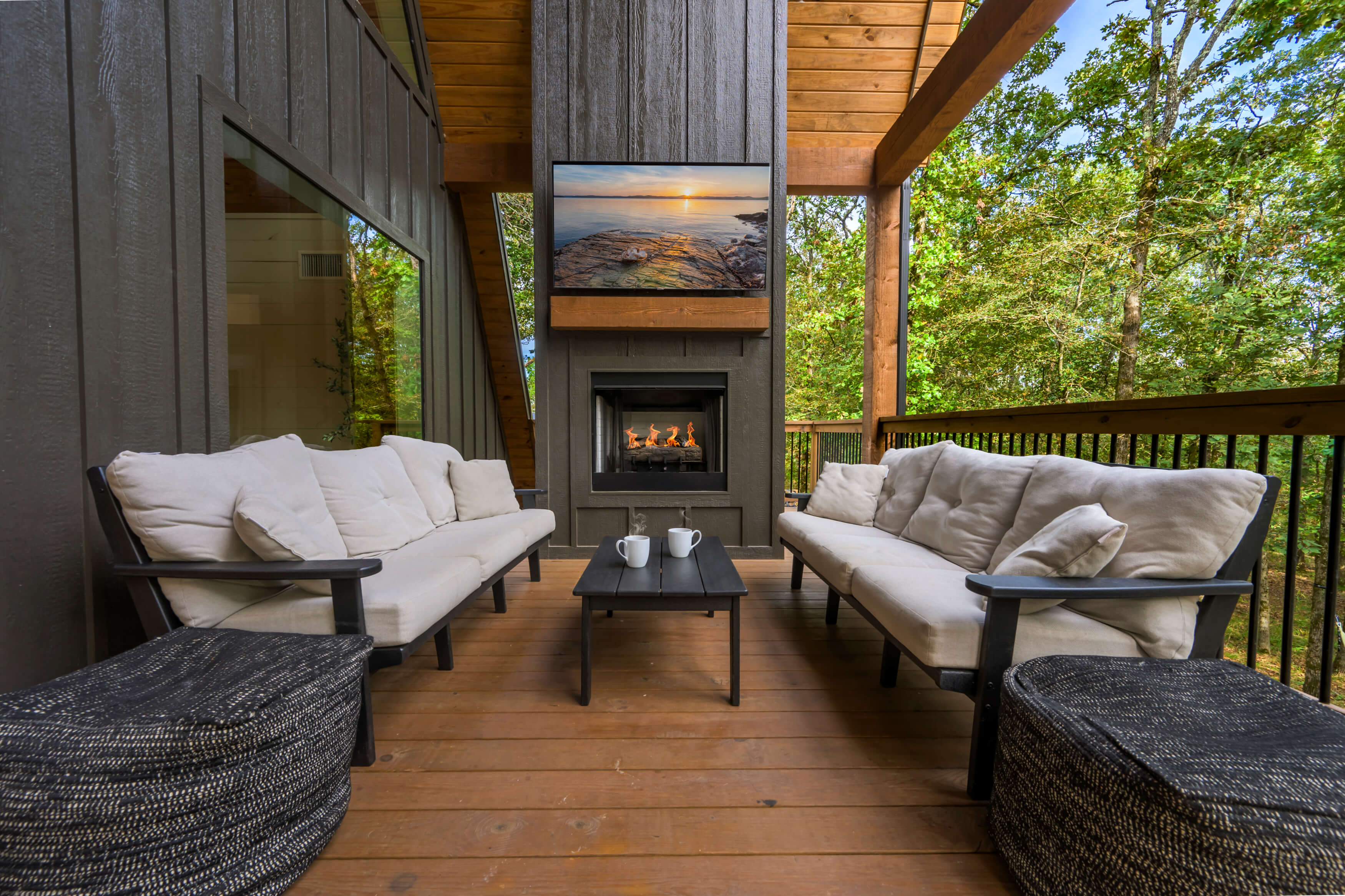 Inviting outdoor patio featuring fireplace, sofas, and lush surroundings.