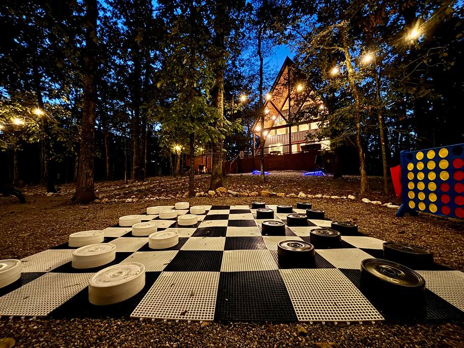 Cozy cabin retreat with outdoor games under twinkling lights in the forest.