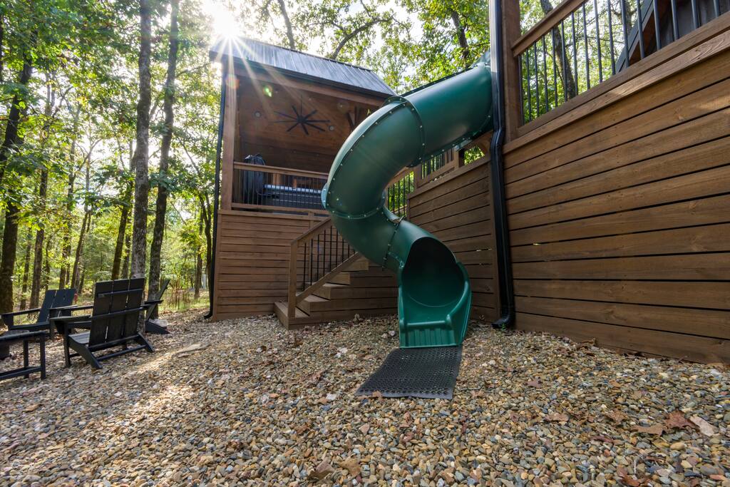 Charming treehouse with spiral slide in a serene forest setting.